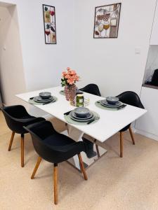a white table with black chairs and a vase with flowers at CFS Apartman in Debrecen