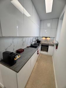 a kitchen with white cabinets and a black counter top at CFS Apartman in Debrecen