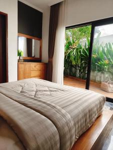 a large bed in a bedroom with a large window at Santo Guesthouse in Canggu