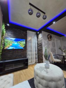 a living room with a tv and a white table at POSEJDON DELUXe 4 in Vrnjačka Banja