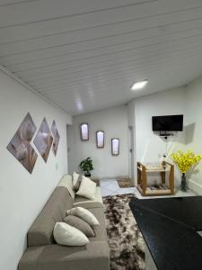 a living room with a couch and a flat screen tv at Casa Dona Vera - Seu Refúgio no Centro Histórico in Mucugê