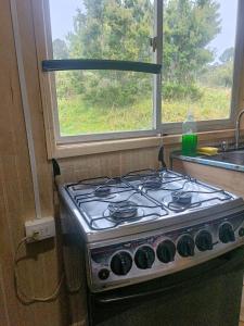 a stove in a kitchen next to a window at Cabaña Mañihueico in Hualaihué