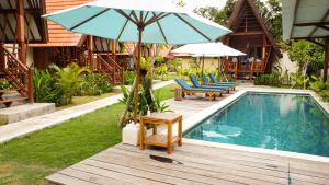 a pool with chairs and an umbrella next to a house at Castaway Island Hostel in Nusa Lembongan