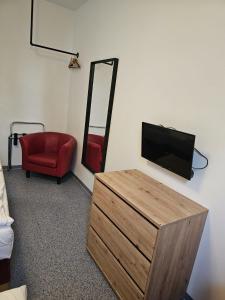 a living room with a television and a red chair at Hotel Astral Vienna in Vienna