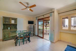 a dining room with a ceiling fan and a table and chairs at Club Esse Residence Capo D'orso in Palau
