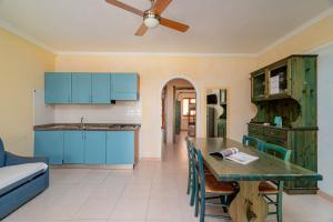a kitchen with blue cabinets and a table with chairs at Club Esse Residence Capo D'orso in Palau