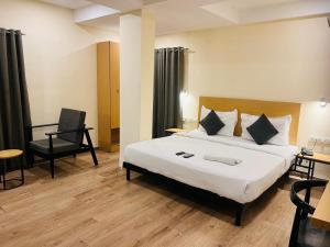 a hotel room with a large bed and a chair at Hotel Enigma in Indore