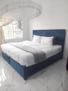 a bed with a blue headboard and a window at Blantyre Airport Lodge in Chileka