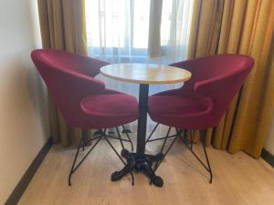a table with two red chairs and a white table and a table and chairs at Güven Suit Otel in Istanbul