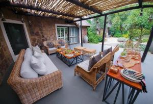 a patio with wicker chairs and a table with a couch at Buccara Waterberg - Molapo in Lephalale