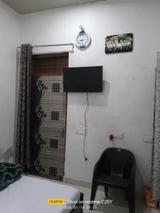 a room with a chair and a television on the wall at Radha Rani homestay in Vrindāvan