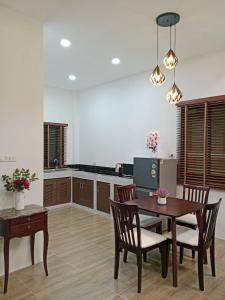 a dining room with a table and chairs and a kitchen at Niramit Pool Villa in Ban Chong Phli