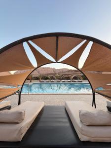 a tent with two beds in front of a pool at Rum Oasis Luxury Camp in Wadi Rum