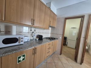 a kitchen with wooden cabinets and a white microwave at Casa da Baixa in Faro