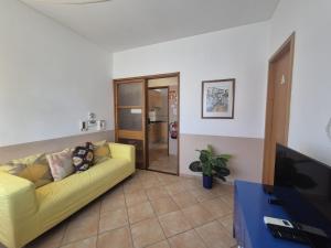 a living room with a yellow couch and a tv at Casa da Baixa in Faro