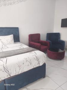 a bedroom with a bed and two chairs at Blantyre Airport Lodge in Chileka