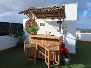 a bar with two chairs and a umbrella at Villadunas - with Luxury Hot Tub and Tiki Roof Top Bar in Corralejo