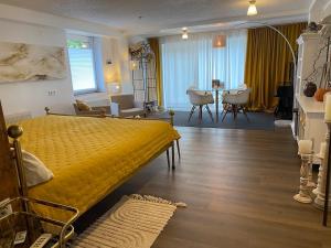 a bedroom with a yellow bed and a dining room at Schiller Ferienwohnung, Pool, Nideggen, Eifel in Nideggen