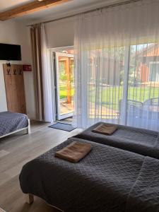 a bedroom with two beds and a large window at Między lasem a wsią-kameralne domki dla dorosłych-jacuzzi i śniadanie w cenie in Grzybowo