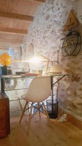 a table and a chair in front of a stone wall at La Casita de Lledó in Vilafamés