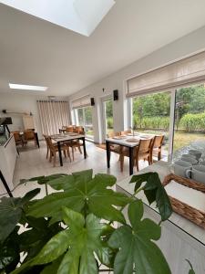 a living room with tables and chairs and a plant at Między lasem a wsią-kameralne domki dla dorosłych-jacuzzi i śniadanie w cenie in Grzybowo