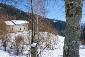 a building in the snow next to a mountain at Baita dal Bigolaro in Vetriola