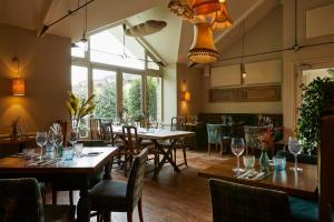 a restaurant with wooden tables and chairs and windows at The Swan in Wedmore