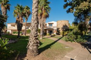 a palm tree in front of a house at Club Esse Residence Capo D'orso in Palau