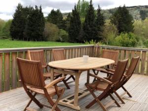 a wooden table and chairs on a wooden deck at Les ferrajals in Rouvenac