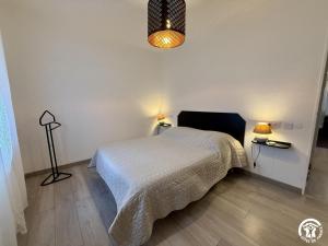 a bedroom with a white bed and a lamp at Les ferrajals in Rouvenac