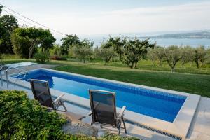two chairs sitting next to a swimming pool at Med oljkami Apartment in Koper
