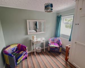 a room with a chair and a table and a mirror at Rosedene Guest House in Pembroke