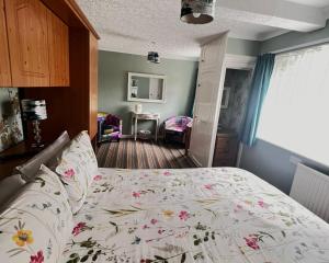 a bedroom with a bed with a floral bedspread at Rosedene Guest House in Pembroke