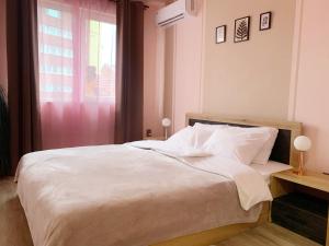 a bedroom with a large white bed with a window at Altavista mountain apartment in Samokov