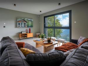 a living room with a couch and a large window at Chalet Confidentiel - OVO Network in Doucy