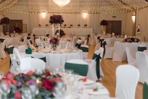 a banquet hall with white tables and white chairs at Cabarfeidh Hotel in Stornoway