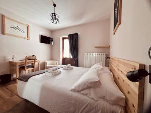a bedroom with a large white bed and a desk at Hotel Piccolo Chalet in Claviere