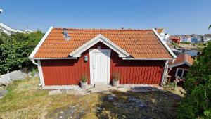 a red house with an orange roof on a hill at Lilla huset in Klädesholmen