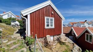 a red house with two chairs in front of it at Lilla huset in Klädesholmen