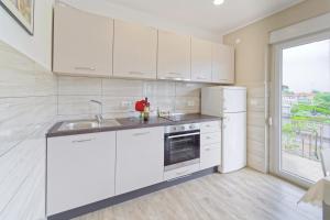a white kitchen with a sink and a refrigerator at Apartment Patrik by Rent Istria in Umag +14 photos