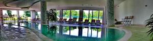 a swimming pool in a building with chairs in it at Szépia Bio and Art Hotel in Zsámbék