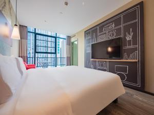 a bedroom with a white bed and a wall with a tv at Ibis Chengdu High-tech Electronics University in Pi