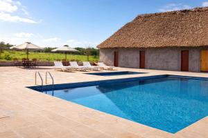 a resort with a swimming pool and a thatch roof at Endeem mara resort in Ololaimutiek