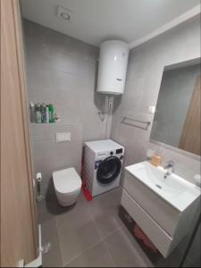 a bathroom with a toilet and a sink and a washing machine at Master Quart studio apartment in Podgorica