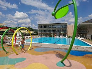 a young boy is playing in a playground near a pool at Szépia Bio and Art Hotel in Zsámbék