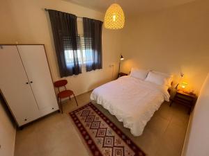 a bedroom with a white bed and a window at Cabin 168 in Neot Golan