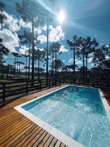 a pool on a wooden deck with a man standing in it at Namastê - Hospedaria de Altitude in Urubici
