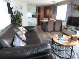 a living room with a leather couch and a table at Veluwe Park Reewold Chalet Eclipse in Putten