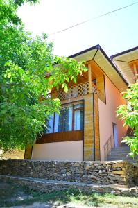 a house with a stone retaining wall and a staircase at Uhum Mountain Guesthouse in Yukary-Ukhum