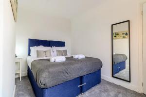 a bedroom with a blue bed with a mirror at Barnwell by Holmesdale Homes in Kettering